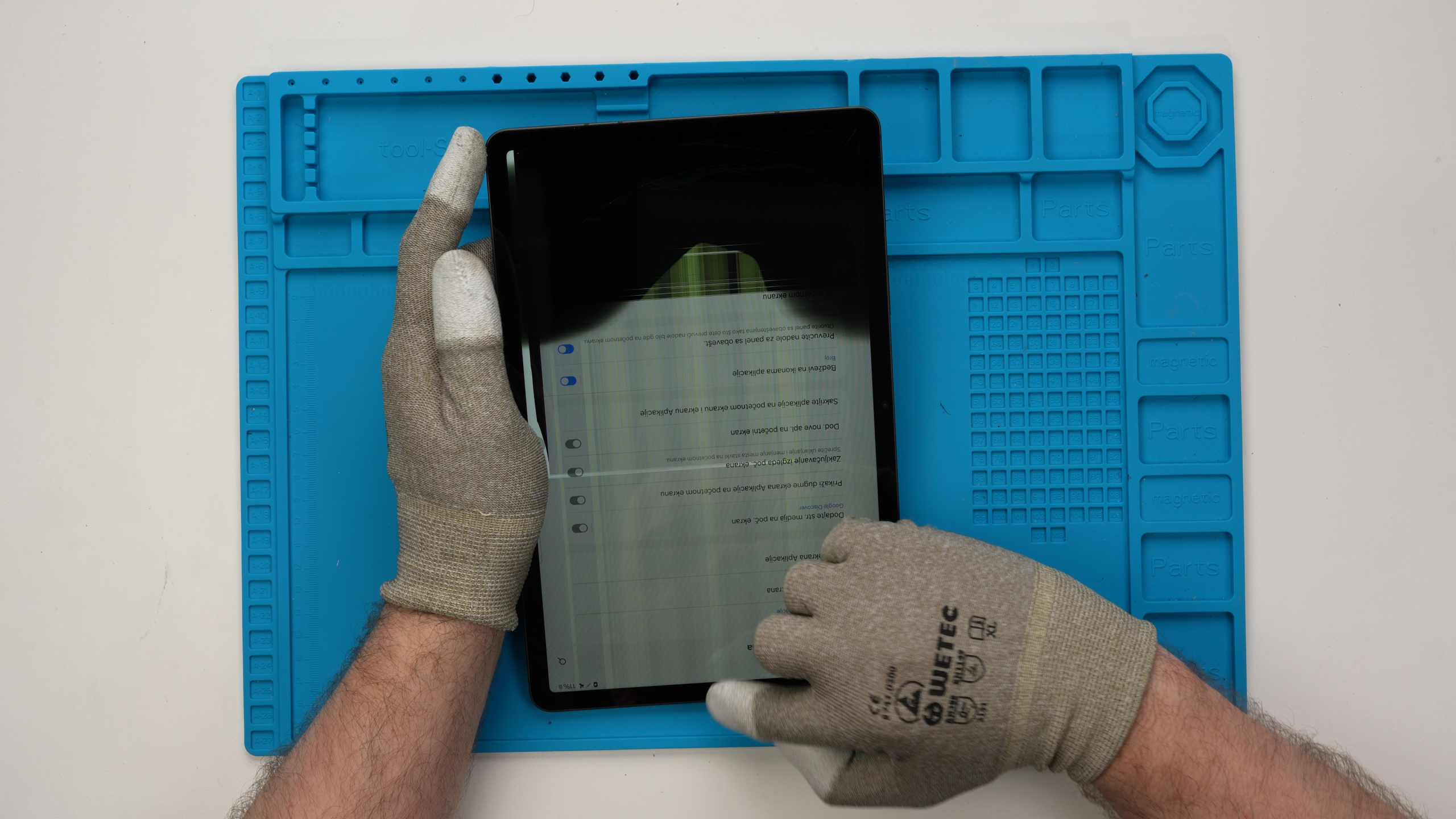 Tablet-Ipad-Reparatur Ein Tablet mit internem Bildschirmbruch und Pixelfehlern wird zur Schadensanalyse von einem Experten gehalten.